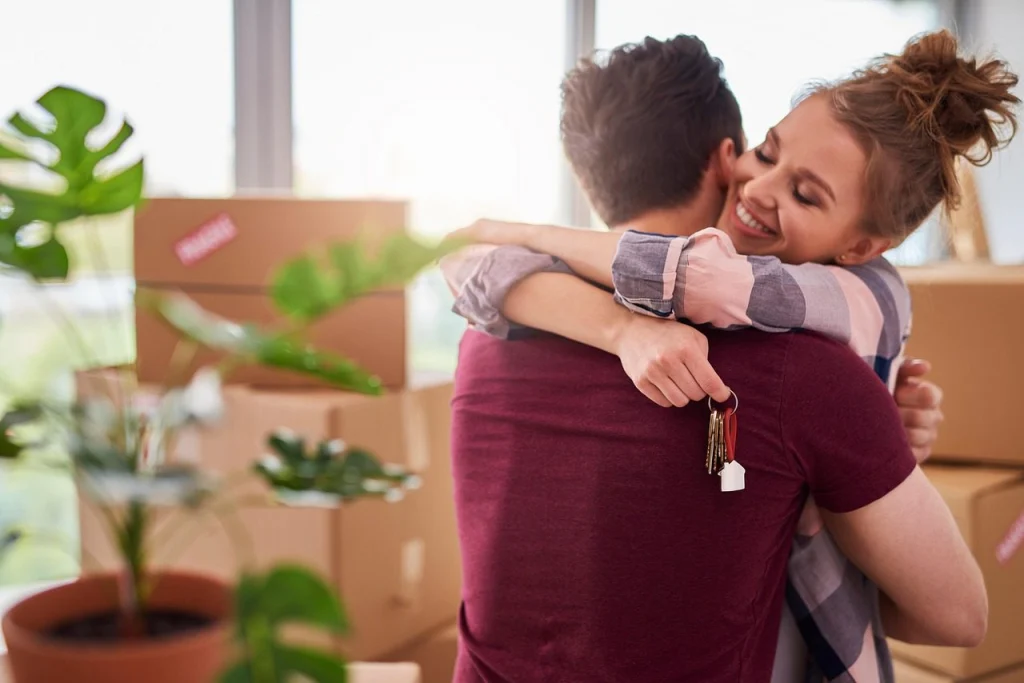Stel omhelst elkaar met de sleutels van hun nieuwe woning